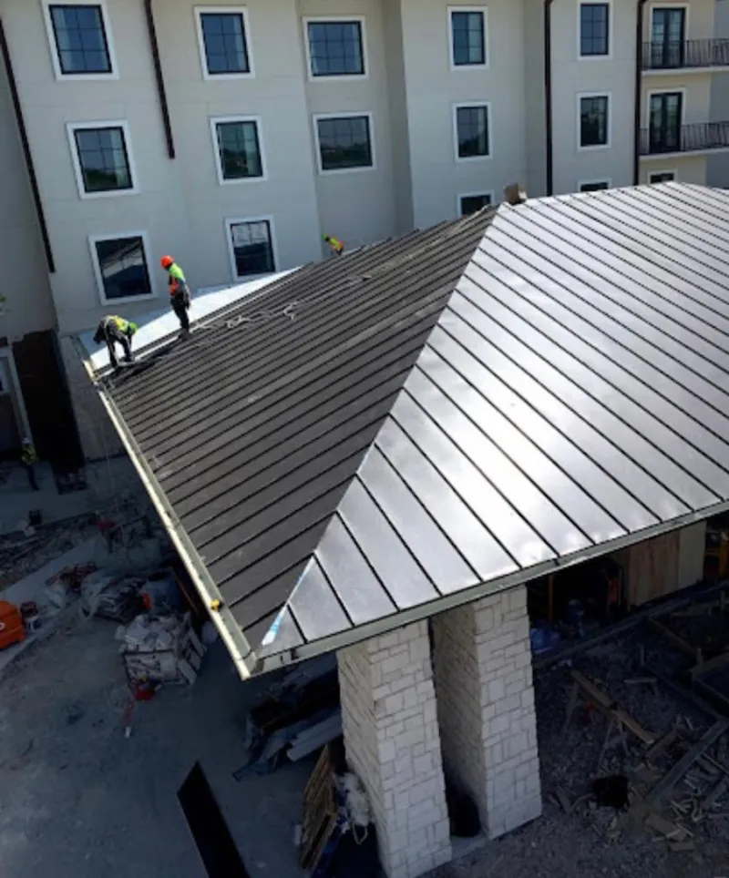 Crew installing standing seam metal roof panels on a commercial project in El Paso